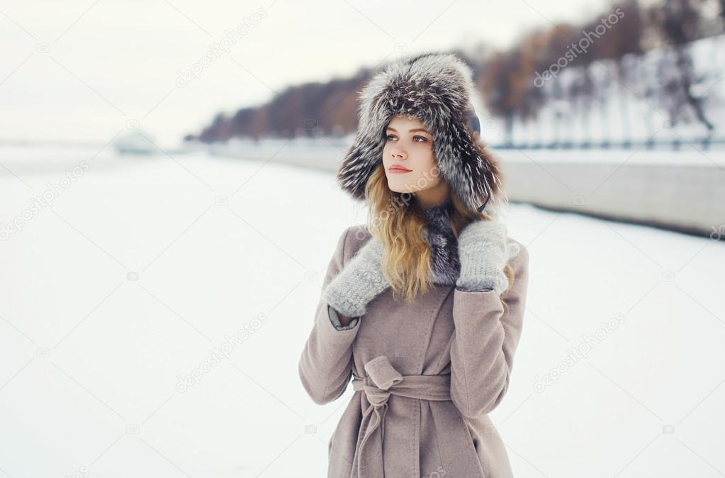 Portrait of a beautiful woman dressed a coat and fur hat in the 