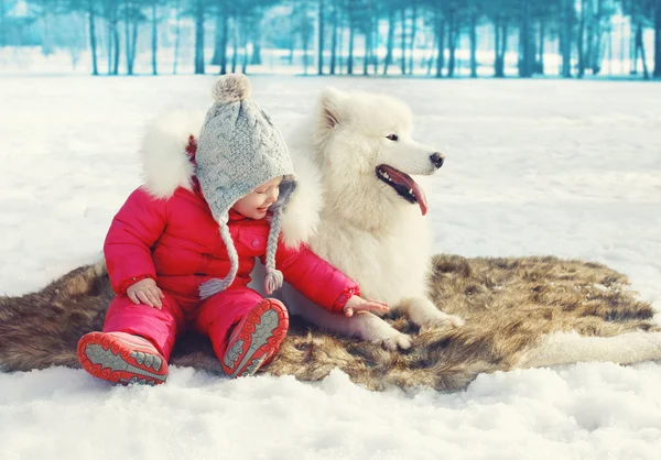 Enfant heureux avec chien Samoyed blanc sur la neige en journée d'hiver — Photo