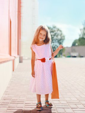 Alışveriş çantası, güneşli su ile beyaz elbiseli güzel küçük kız