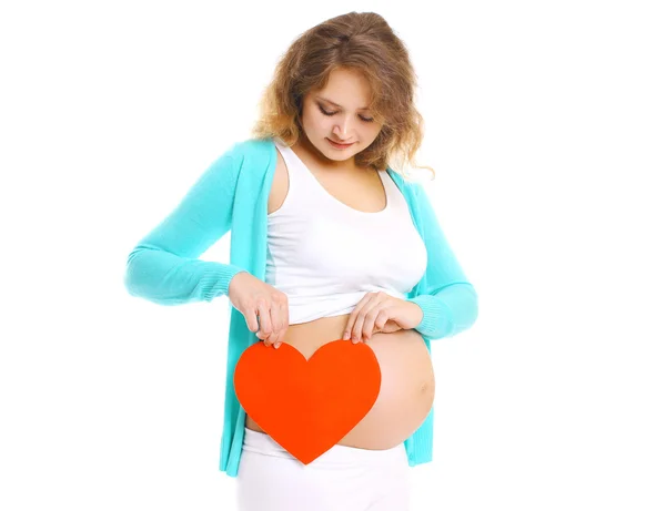 Jeune femme enceinte et grand coeur rouge dans les mains sur un dos blanc — Photo