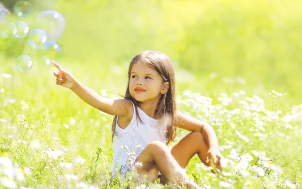 Niño sentado en la hierba en el campo de verano, día soleado — Foto de Stock