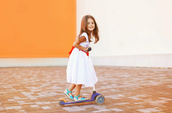 Menina feliz no vestido na scooter ao ar livre — Fotografia de Stock