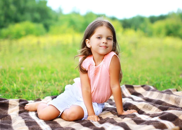 격자 무늬 outdoo에 앉아 행복 한 작은 소녀의 여름 초상화 — 스톡 사진