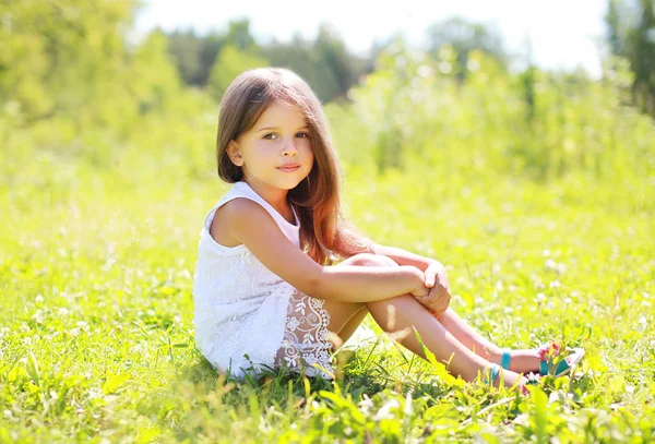 Soliga porträtt av vacker liten flicka sitter på gräset i — Stockfoto