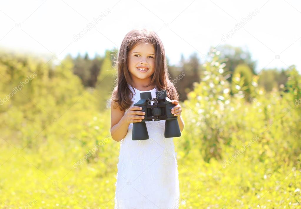 Portrait of smiling child with binoculars outdoors in sunny summ