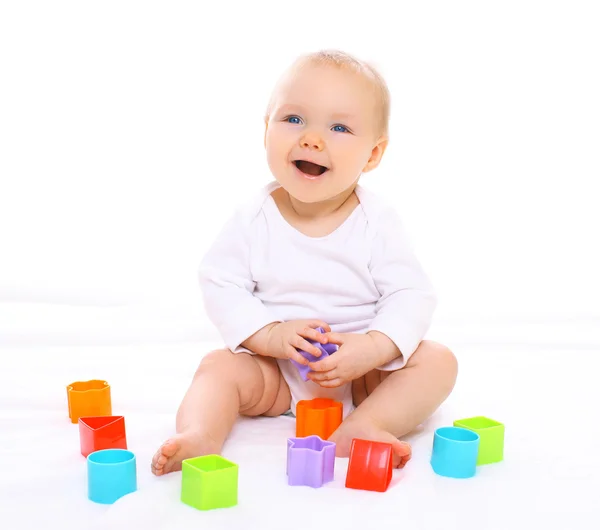 Engraçado bebê sentado brincando com brinquedos coloridos e rindo — Fotografia de Stock