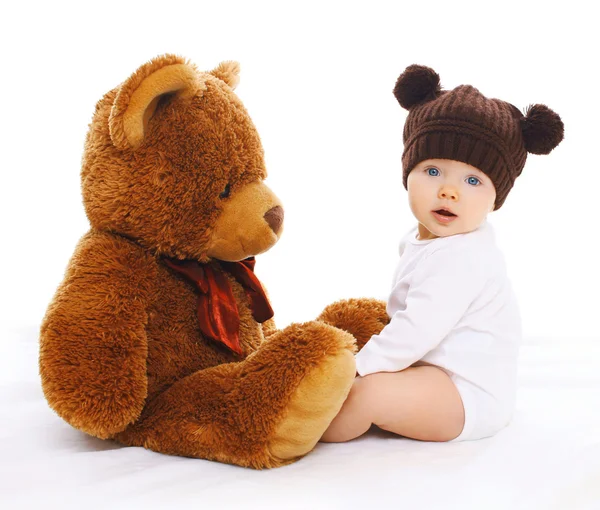 Portrait of cute baby in knitted brown hat with big teddy bear — Stock Photo, Image