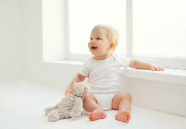 Beyaz r evde oturan oyuncak ayı oyuncak sevimli gülümseyen bebek