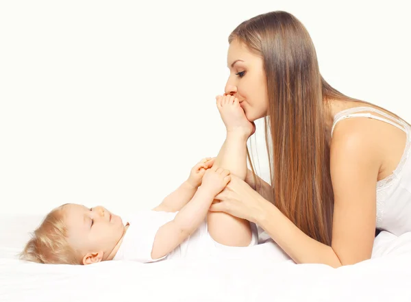 Glückliche junge Mutter und Baby zu Hause zusammen auf dem Bett liegend — Stockfoto