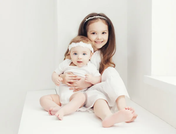 Two sisters little girls in white room at home near window — Stock Photo, Image