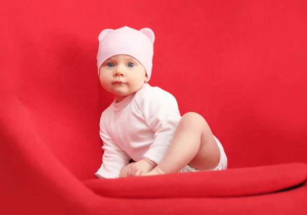 Bambino in cappello seduto sulla poltrona rossa a casa — Foto Stock