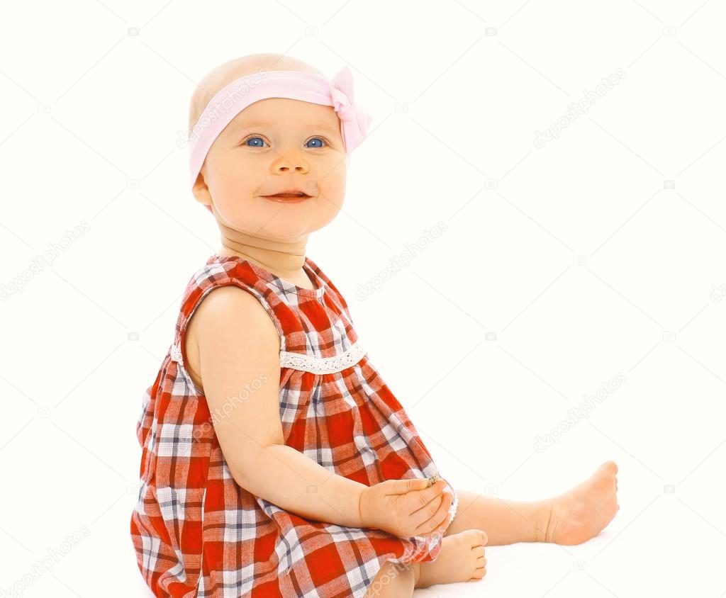 Portrait of cute little baby girl in the dress sitting on a whit