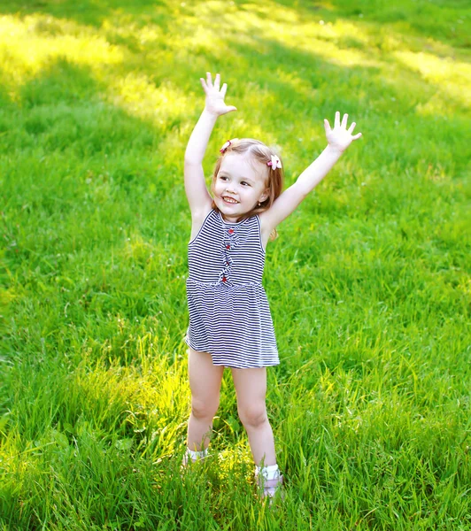 Lilla flickan barn ha roligt på gräset i solig sommardag — Stockfoto