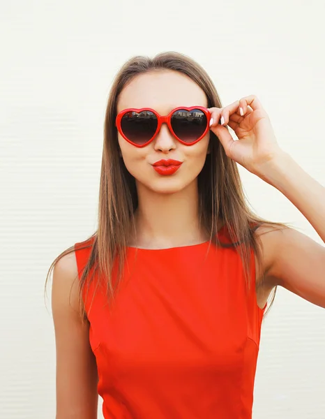 Portrait de jolie femme aux lunettes de soleil rouges soufflant lèvres havi — Photo