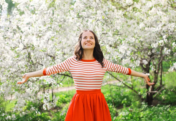 Beautiful happy young woman enjoying smell in a flowering spring