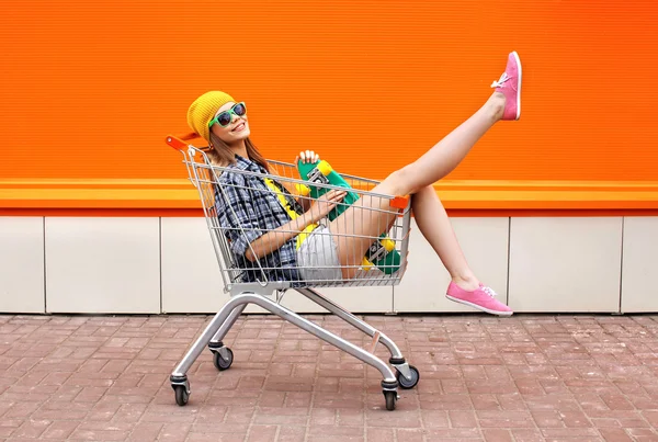 Fashion hipster cool girl with skateboard in shopping cart havin — Stock Photo, Image