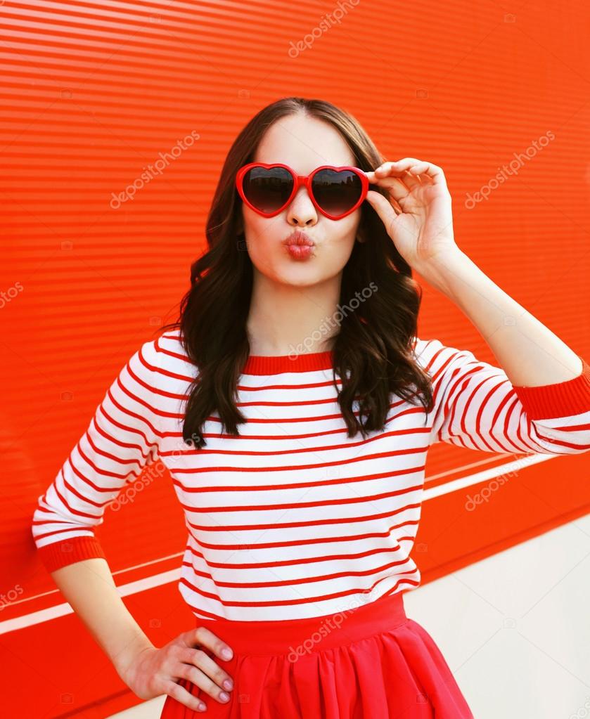 Portrait of pretty woman in red sunglasses blowing lips having f