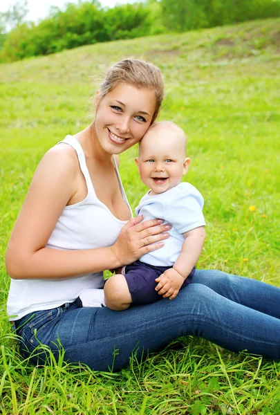 Portrait of happy smiling mother and son child sitting on the gr — Stock Photo, Image