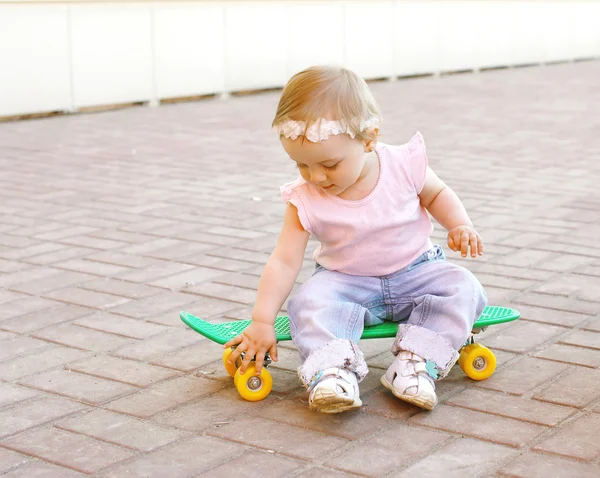 Cute baby sitting on the skateboard outdoors in city — Stock Photo, Image