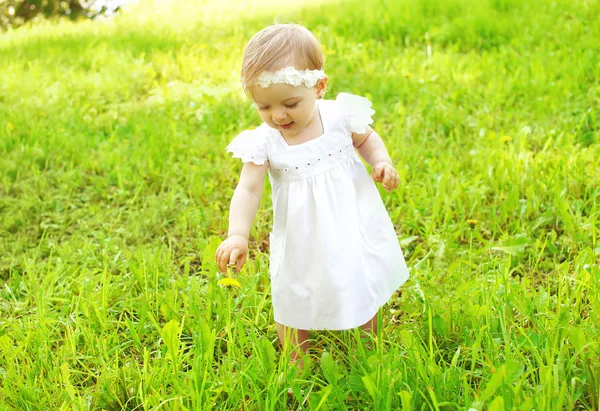 Niedliches Baby, das an einem sonnigen Sommertag draußen auf dem Gras spaziert — Stockfoto