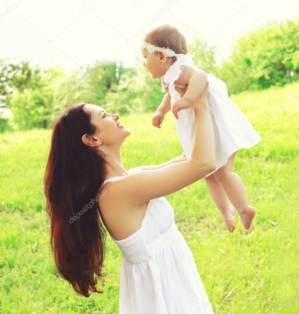 Happy young mother and baby together outdoors in sunny summer da
