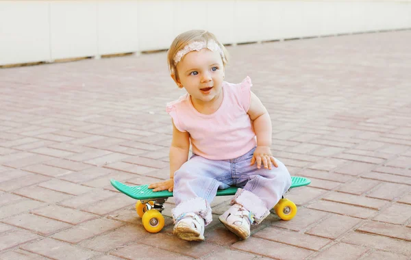 Retrato de bebê bonito sentado no skate ao ar livre na cidade — Fotografia de Stock