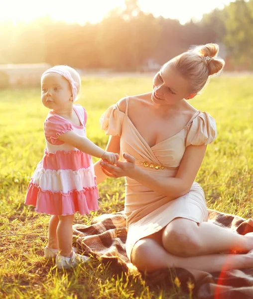 Feliz jovem mãe e bebê pequena filha vestindo um vestido toge — Fotografia de Stock