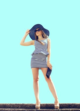 Fashion beautiful blonde woman wearing a striped dress, straw ha