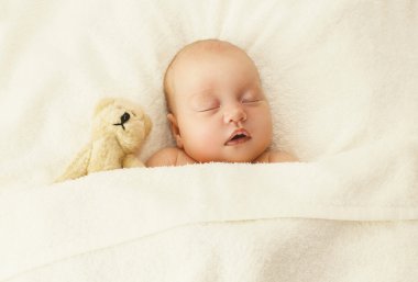 Portrait of cute baby sleeping together with teddy bear toy on t clipart