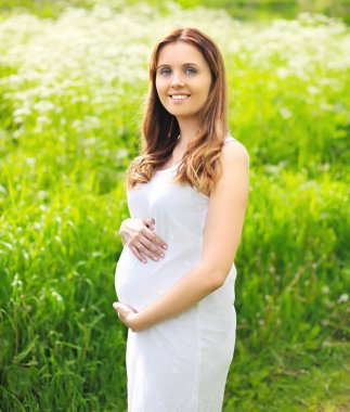 Beyaz dres güzel gülümseyen genç hamile kadın portresi