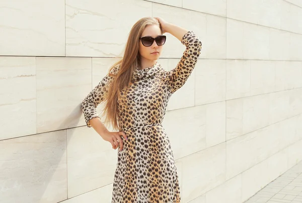 Beautiful blonde woman wearing a leopard dress and sunglasses po — Stockfoto