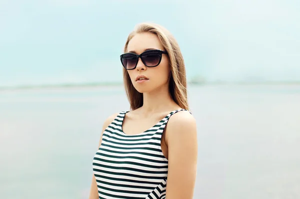 Portrait of beautiful young blonde woman in sunglasses and strip — Stock fotografie