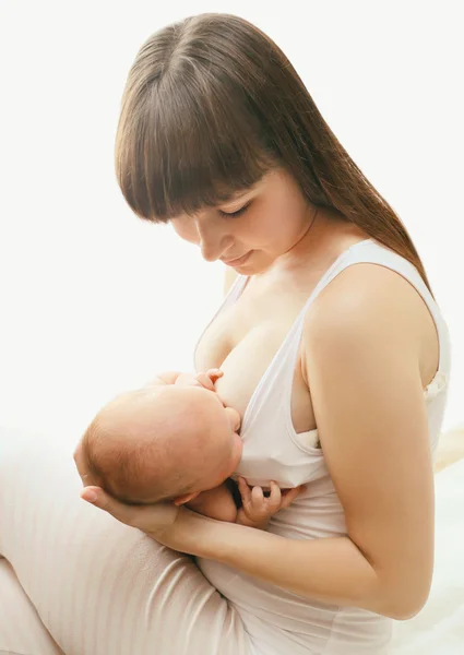 Mother holding on hands baby and feeding breast at home, soft ph — Zdjęcie stockowe