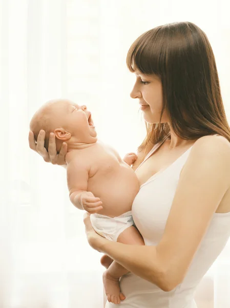 Portrait of baby yawning on hands of mother at home — Stock Photo, Image