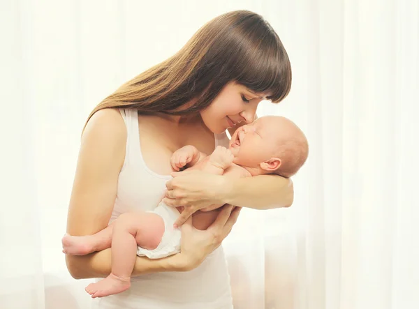 Porträtt av glad ung mamma och baby på händer hemma — Stockfoto