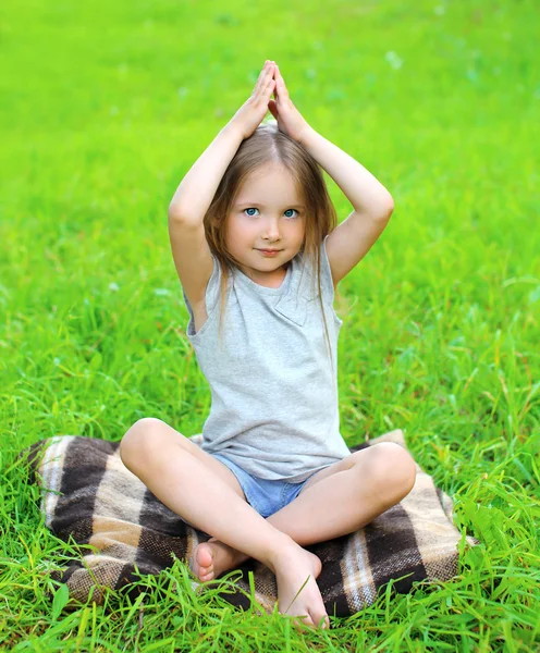 Niña niña en la hierba hace ejercicio de yoga al aire libre — Foto de Stock