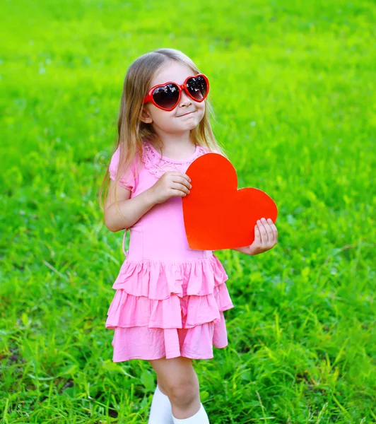 Portrait de petite fille en robe, lunettes de soleil avec papier rouge entendre — Photo