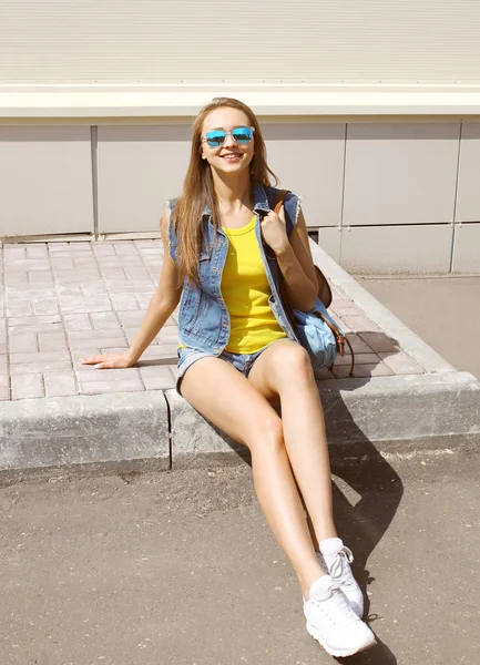 Bella donna sorridente indossa un occhiali da sole e jeans vestiti con — Foto Stock