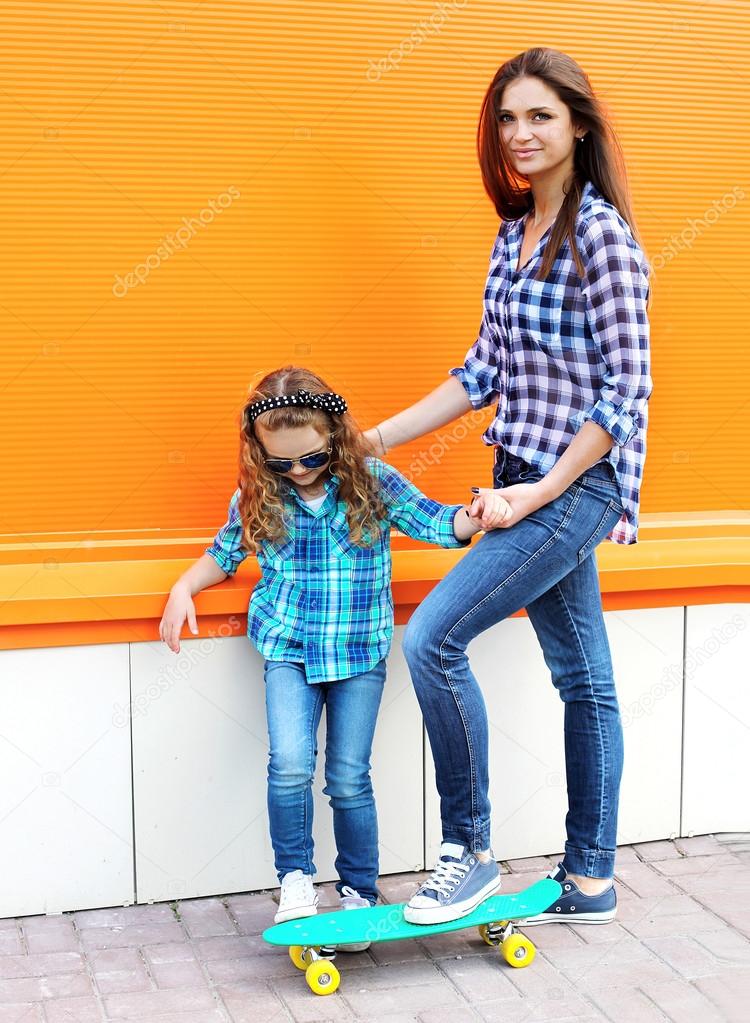 Fashion family concept - mother and child riding on the skateboa