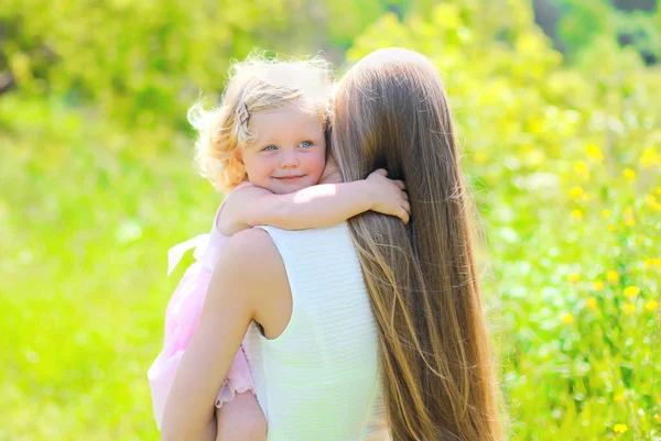 Sunny portrait of happy child hugging mother in summer day — Φωτογραφία Αρχείου
