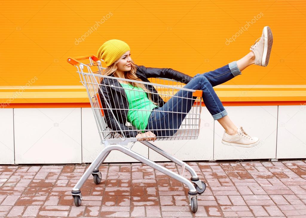 Fashion woman riding having fun in shopping trolley cart over co