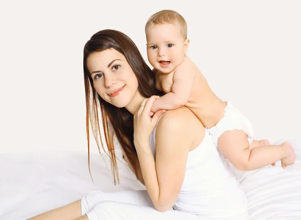 Yatakta evde bebekle oynarken mutlu genç anne — Stok fotoğraf