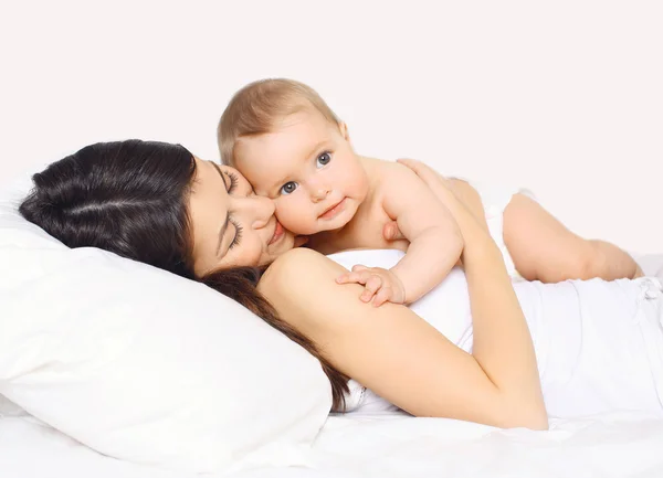 Madre cariñosa acostada con un lindo bebé juntos en la cama en casa — Foto de Stock