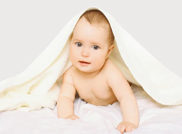 Retrato de bebé lindo bajo la toalla en la cama en casa —  Fotos de Stock