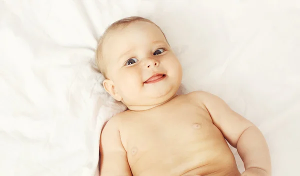 Retrato de bebê sorridente deitado na cama em casa, vista superior — Fotografia de Stock