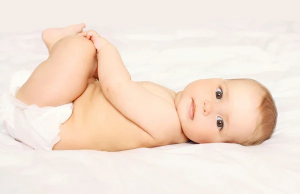 Retrato de bebé lindo en pañales acostado en la cama en casa Fotos de stock