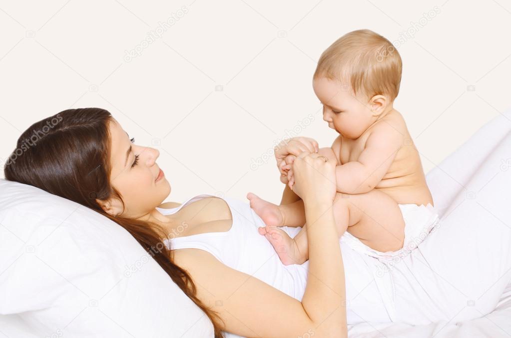 Mother playing with baby on the bed at home