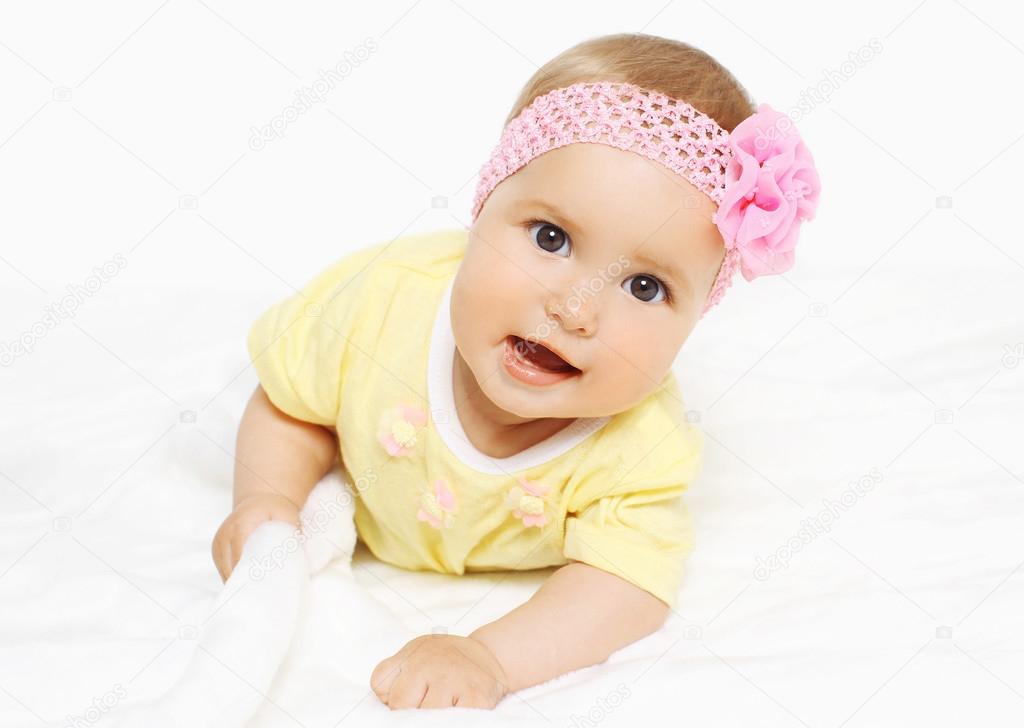 Portrait of cute baby in headband with flower lying 