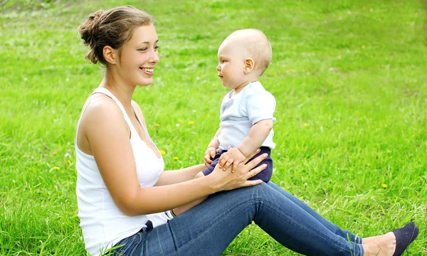 Feliz sonriente madre e hijo niño sentado en la hierba en Summe —  Fotos de Stock