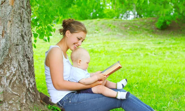 Mãe e bebê leitura livro juntos na grama — Fotografia de Stock